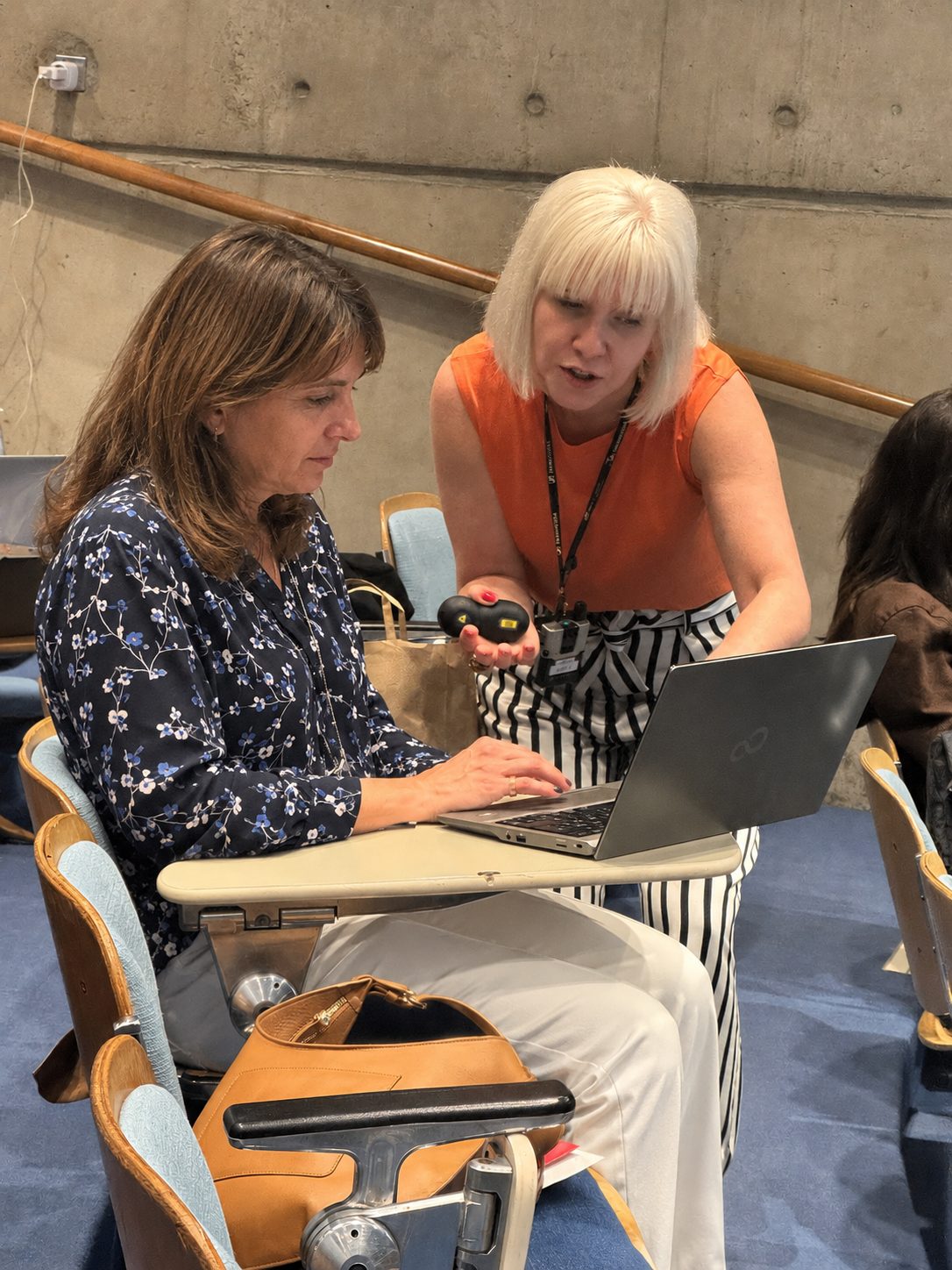 Brooke Gallagher crouched beside a Trinity College Dublin participant, coaching them through a task on their laptop.